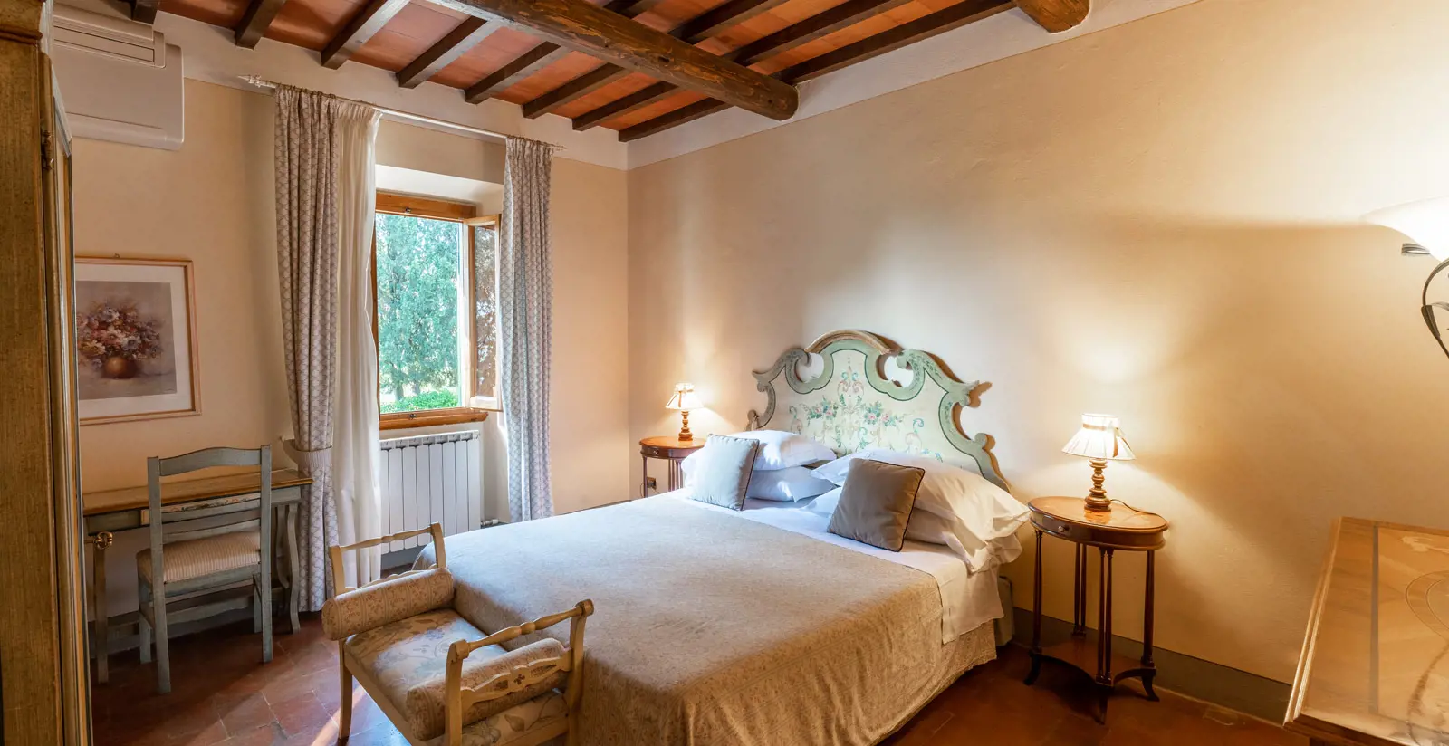 Camera con letto matrimoniale, testiera dipinta e soffitto a travi a vista