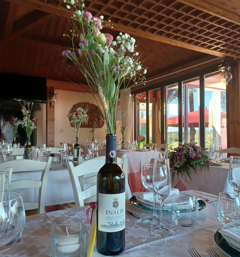 Tavoli con una bottiglia di vino Chianti classico Inalbi apparecchiati per gli invitati